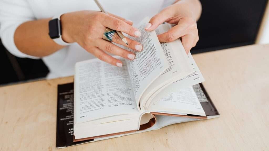 person wearing silver ring holding white book page