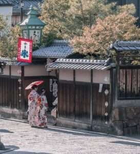 two women wearing traditional dresses standing near house