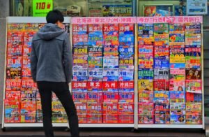 standing man wearing gray hoodie in front of magazine in rack